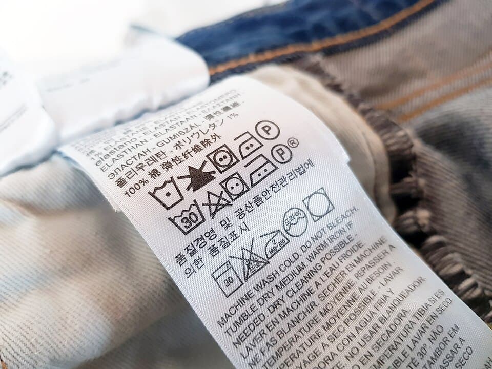 Hands carefully washing a delicate fabric garment in a basin of cool water with gentle detergent
