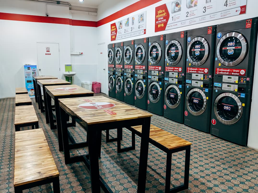 Clean modern self-service laundromat interior in Kuala Lumpur with rows of front-load washing machines and digital payment terminals